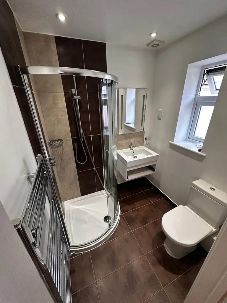 Bathroom installation with corner shower, basin, toilet and tiled flooring